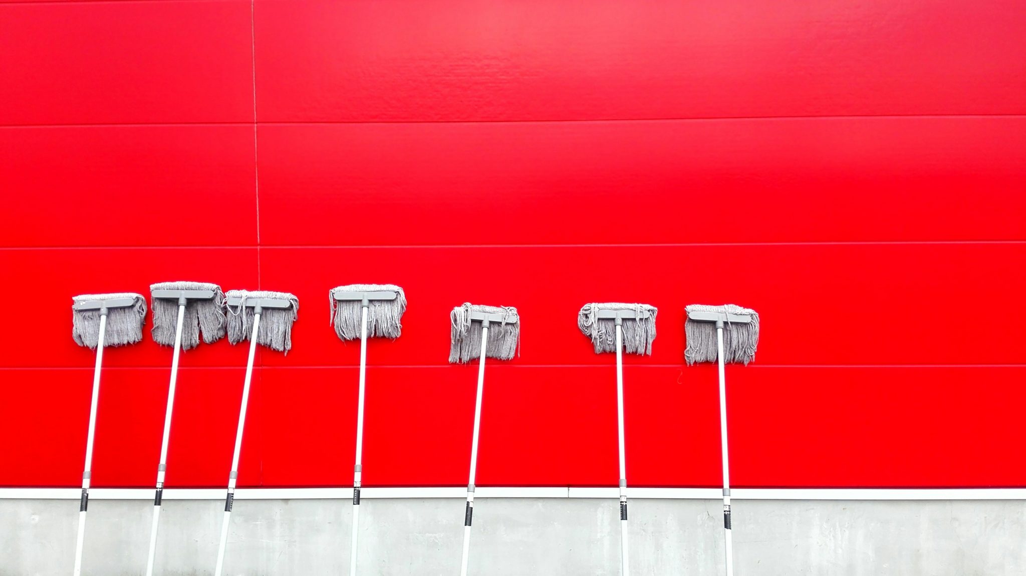 Several Mops Propped Up Against a Wall
