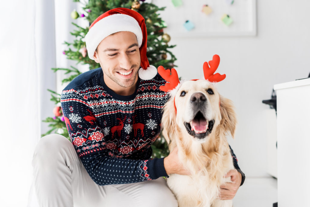 An image of a man in a Christmas hat and his dog