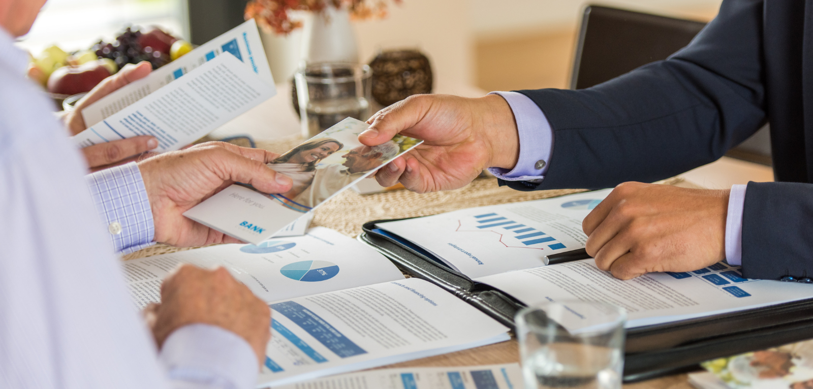 Individuals exchanging professional brochures.