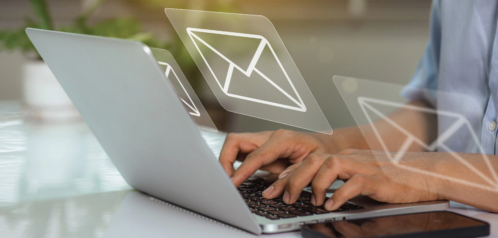 Hand typing on a laptop with illustration of envelope floating above